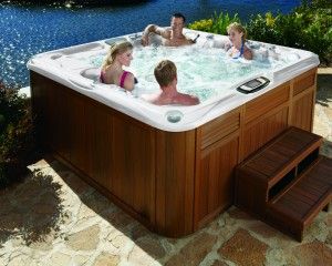 Four people relaxing in a hot tub installed by the water.