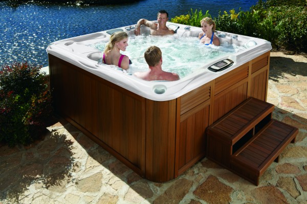Four people relaxing in a hot tub installed by the water.