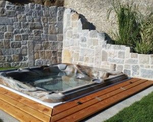 In-ground hot tub installation surrounded by stone masonry walls.