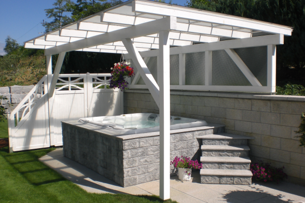 Sundance Spas hot tub under a white pergola built into a grey brick surround.