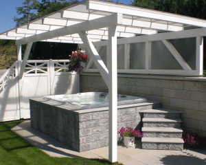 Sundance Spas hot tub under a white pergola built into a grey brick surround.